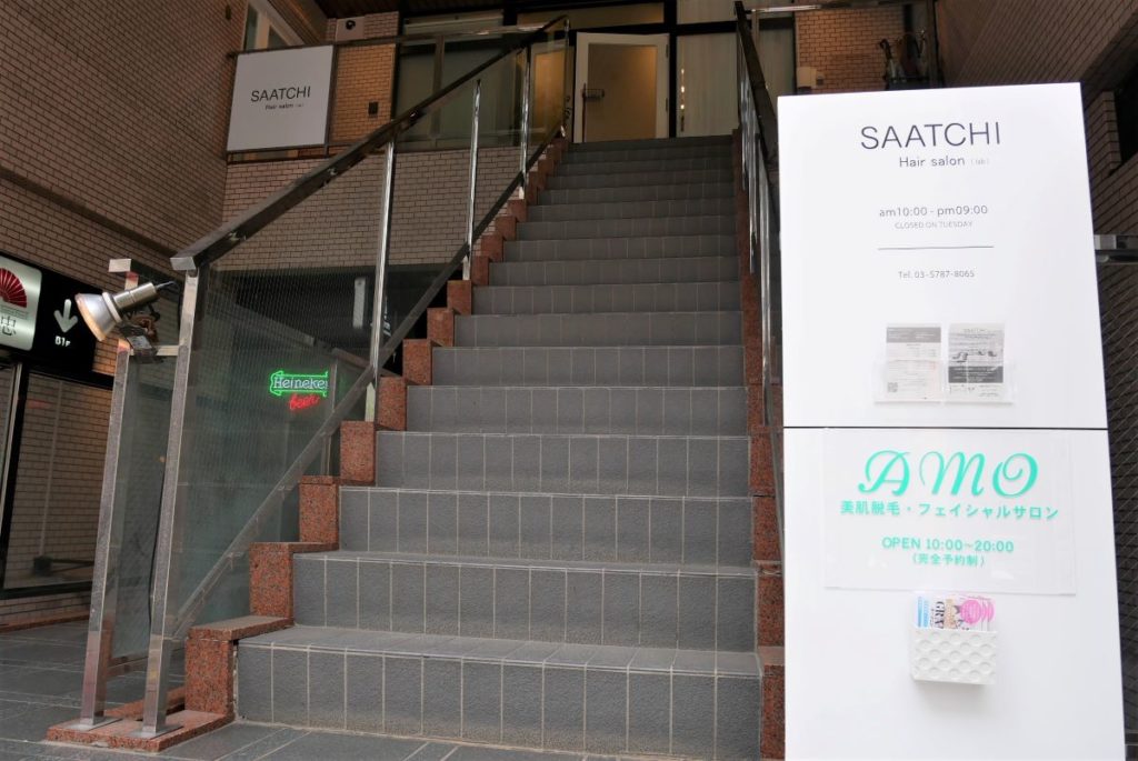 AMOは世田谷通り沿いにあります。AMOのロゴが入った看板の横の階段を上がった2階がサロンです。